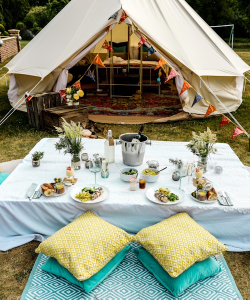 A photo of a glamping tent with a table outside with food
